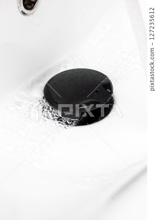This is a closeup picture capturing a sink drain with water flowing out of it 127235612