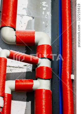 A long row of red and white pipes mounted on a wall surface A long row of red and white pipes mounted on a wall surface 127235619