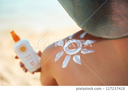Sun cream on tanned shoulder with sun shape . Sun protection. Beautiful woman in bikini applying  Solar Cream. Skin and body care.Portrait of female holding suntan lotion or moisturizing sunblock 127237428