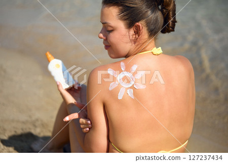 Suntan Lotion. Sexy Young Woman in Bikini Applying Sunscreen Solar Cream.Sun Protection. Sun Cream. Skin and Body Care.Girl Holding Moisturizing Sunblock. Sun shape on the shoulder. Skin Protection. Suntan Lotion. Sexy Young Woman in Bikini Applying Sunscreen Solar Cream.Sun Protection. Sun Cream. Skin and Body Care.Girl Holding Moisturizing Sunblock. Sun shape on the shoulder. Skin Protection. 127237434