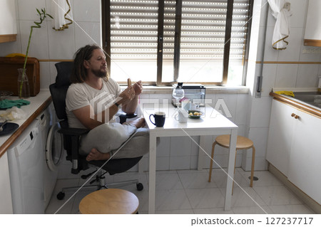 Man eating breakfast in messy kitchen at home 127237717