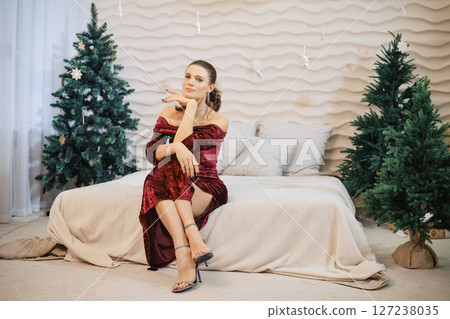 Model poses elegantly in a stylish outfit surrounded by festive decorations at home 127238035
