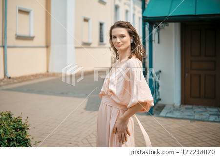 Confidence shines through as a woman poses in a charming urban setting with soft sunlight 127238070