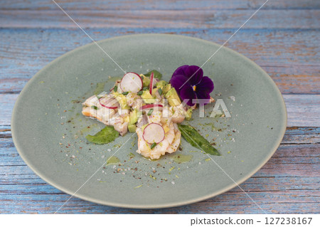 Fresh dorade and shrimp ceviche with avocado, radish, and edible flower on a decorated plate 127238167