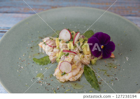 Fresh dorade and shrimp ceviche with avocado, radish, and edible flower on a decorated plate Fresh dorade and shrimp ceviche with avocado, radish, and edible flower on a decorated plate 127238194