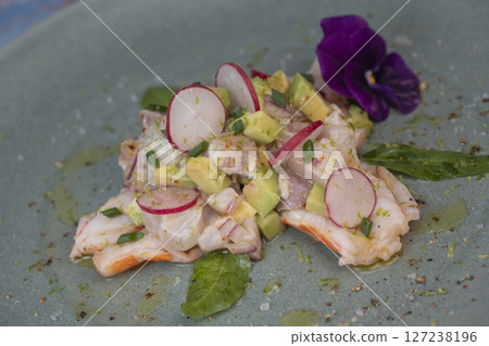 Fresh dorade and shrimp ceviche with avocado, radish, and edible flower on a decorated plate Fresh dorade and shrimp ceviche with avocado, radish, and edible flower on a decorated plate 127238196