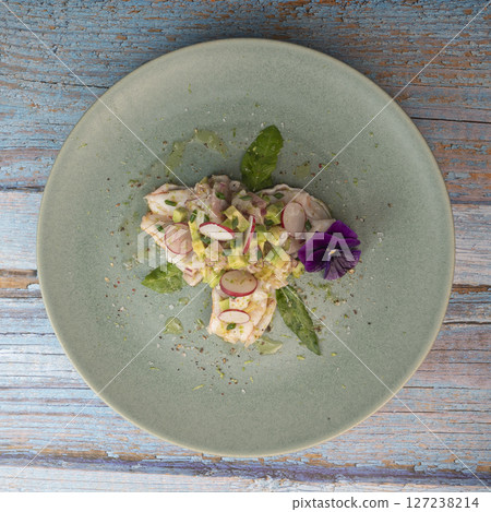 Fresh dorade and shrimp ceviche with avocado, radish, and edible flower on a decorated plate Fresh dorade and shrimp ceviche with avocado, radish, and edible flower on a decorated plate 127238214