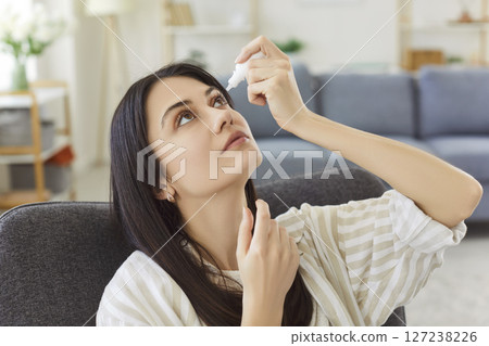 Young woman applying eye drops to relieve dryness, irritation and maintain eye moistened and healthy. Young woman applying eye drops to relieve dryness, irritation and maintain eye moistened and healthy. 127238226