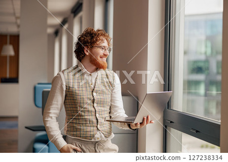 A Stylish and Professional Individual Working by the Window in a Modern Office Environment 127238334