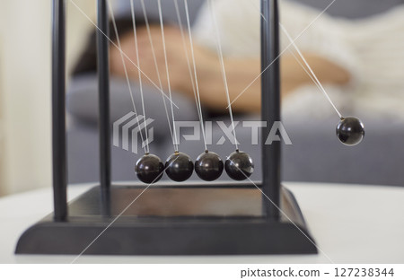 Newton cradle device on desk, balance, perpetual swinging motion, corporate business souvenir Newton cradle device on desk, balance, perpetual swinging motion, corporate business souvenir 127238344