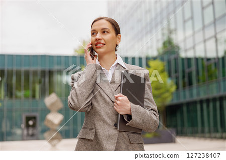A driven businesswoman makes a key call in a busy urban setting, highlighting her ambition A driven businesswoman makes a key call in a busy urban setting, highlighting her ambition 127238407
