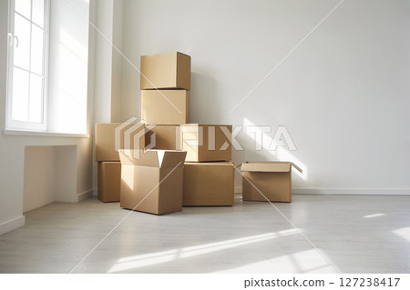 Pile of carton boxes in empty room against white wall 127238417