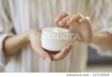 Close up of female hands holding cosmetic cream bottling jar, lady trying moisturizing revitalizing  127238420