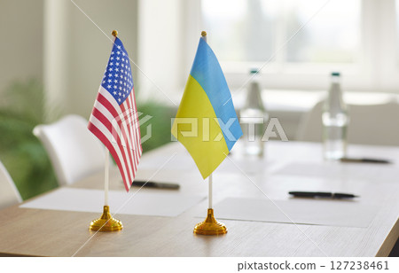 United States and Ukraine flags standing on table together with boardroom background 127238461