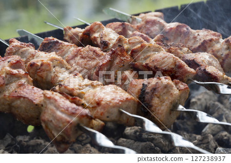 closeup of some meat skewers being grilled in a barbecue closeup of some meat skewers being grilled in a barbecue 127238937