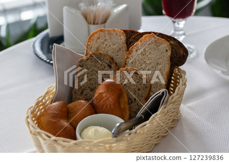 Bread in basket. White and black sliced bread, butter and pies in a basket on the table in the restaurant Bread in basket. White and black sliced bread, butter and pies in a basket on the table in the restaurant 127239836