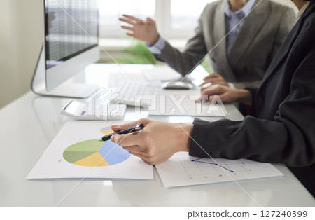 Two female colleagues working together, analyzing financial charts and discussing business results. Two female colleagues working together, analyzing financial charts and discussing business results. 127240399