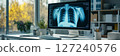 A medical office desk is shown with a computer screen displaying an X-ray image 127240576