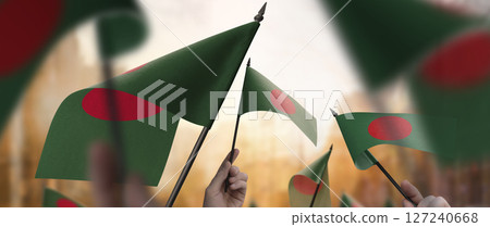Bangladesh flags in their hands on a blurred urban background 127240668