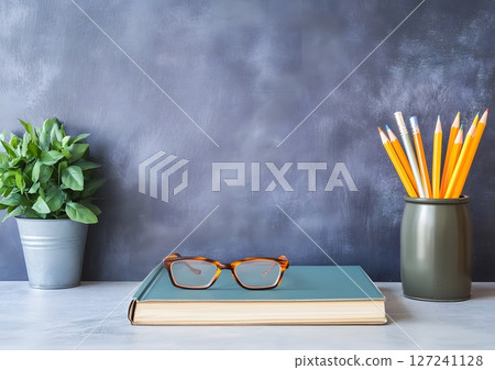 tidy student desk with closed book, glasses, and pencil on neutral surface 127241128
