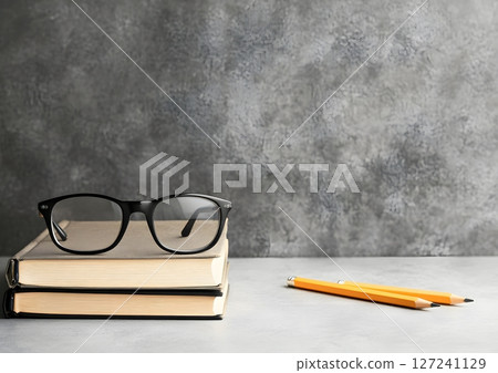 tidy student desk with closed book, glasses, and pencil on neutral surface 127241129