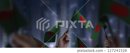 Bangladesh flags in their hands on a blurred urban background Bangladesh flags in their hands on a blurred urban background 127241526