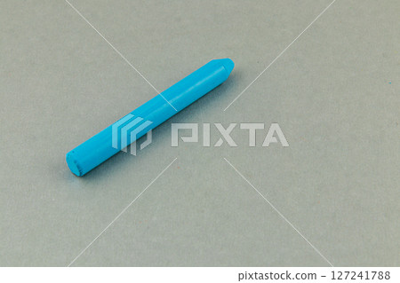 Bright blue crayon placed on a smooth gray surface 127241788