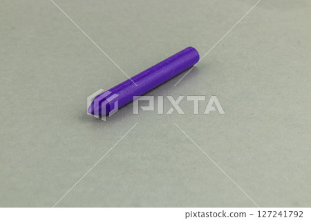 Purple crayon rests on a plain surface in bright lighting Purple crayon rests on a plain surface in bright lighting 127241792