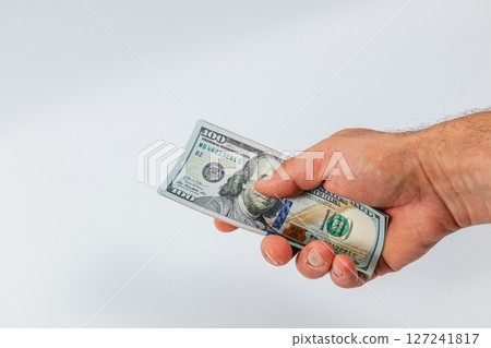Hand holding a hundred dollar bill in clear focus Hand holding a hundred dollar bill in clear focus 127241817