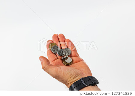 Hand holding various coins against a neutral background 127241829