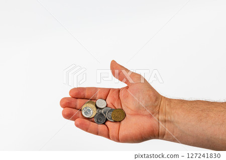 Hand holding various coins against a plain background 127241830