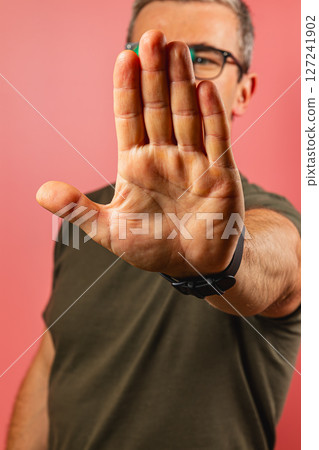 Man demonstrating a stop gesture against a pink background 127241902