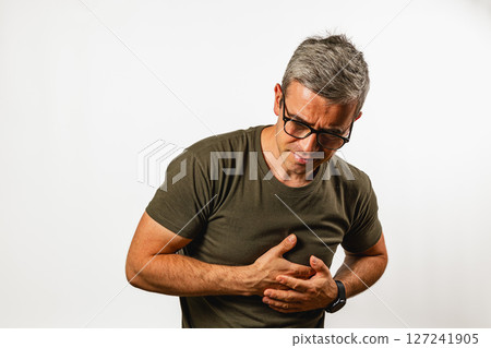 Man experiences stomach pain while standing indoors Man experiences stomach pain while standing indoors 127241905