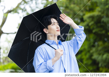 Young man holding a parasol Young man holding a parasol 127241994
