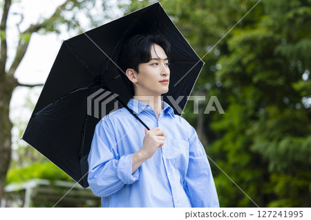 Young man holding a parasol Young man holding a parasol 127241995