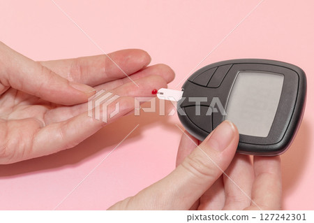 Woman doing blood sugar test Woman doing blood sugar test 127242301