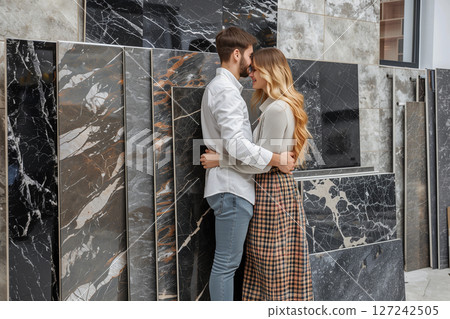 Young couple enthusiastically selecting large granite tiles for home renovation 127242505
