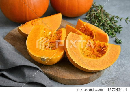 Cutting Fresh Pumpkins on Board with napkin. Baked pumpkin. Sliced raw Cucurbita and spices for preparing soup, warm salad, fall dish. Thanksgiving food. Roasted vegetable in olive oil salt, herbs. Cutting Fresh Pumpkins on Board with napkin. Baked pumpkin. Sliced raw Cucurbita and spices for preparing soup, warm salad, fall dish. Thanksgiving food. Roasted vegetable in olive oil salt, herbs. 127243444