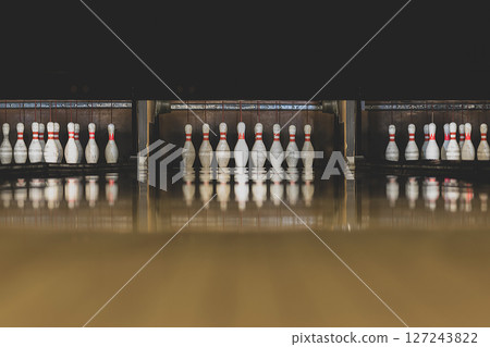 Old and dark parquet bowling track with white pins 127243822