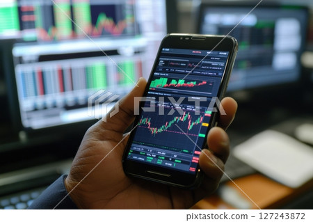Man trader using smartphone checking graph exchange on blue monitor with online data background. Person using phone investing application. Stock market, trading cryptocurrency on app. Online business 127243872