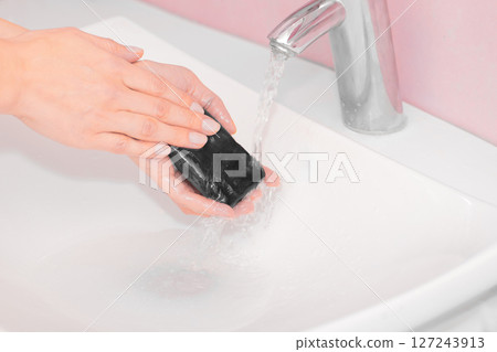 Woman washing hands with black soap over sink Woman washing hands with black soap over sink 127243913