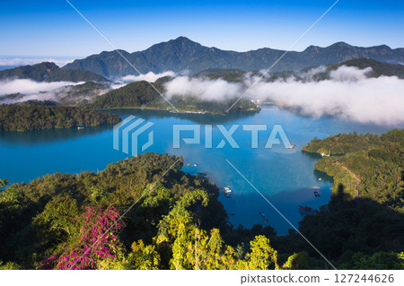 日月潭風景—美麗的湖面景觀映照出奇幻的日出天空。亞洲台灣南投縣著名的旅遊景點。 日月潭風景—美麗的湖面景觀映照出奇幻的日出天空。亞洲台灣南投縣著名的旅遊景點。 127244626
