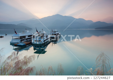 日月潭風景—美麗的湖面景觀映照出奇幻的日出天空。亞洲台灣南投縣著名的旅遊景點。 日月潭風景—美麗的湖面景觀映照出奇幻的日出天空。亞洲台灣南投縣著名的旅遊景點。 127244627
