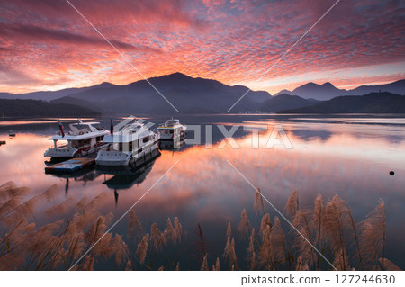 日月潭風景—美麗的湖面景觀映照出奇幻的日出天空。亞洲台灣南投縣著名的旅遊景點。 日月潭風景—美麗的湖面景觀映照出奇幻的日出天空。亞洲台灣南投縣著名的旅遊景點。 127244630