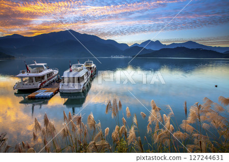 日月潭風景—美麗的湖面景觀映照出奇幻的日出天空。亞洲台灣南投縣著名的旅遊景點。 日月潭風景—美麗的湖面景觀映照出奇幻的日出天空。亞洲台灣南投縣著名的旅遊景點。 127244631