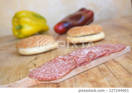 Sliced Salami and Fresh Buns on a Wooden Board with Green Onions Sliced Salami and Fresh Buns on a Wooden Board with Green Onions 127244901