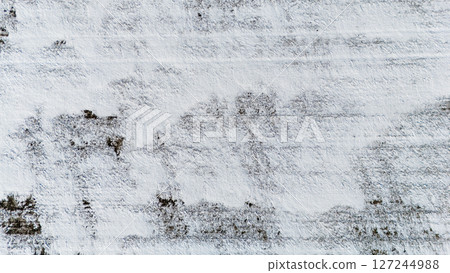 Drone view over a snow covered agriculture field with cultivated rows from crops. Drone view over a snow covered agriculture field with cultivated rows from crops. 127244988