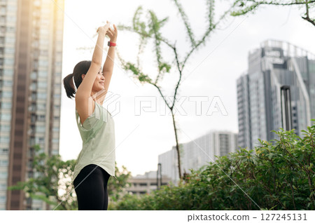 Happy asian woman 30s fitness yoga workout. Stretching exercise urban city sunset. Healthy lifestyle for wellness healthcare reduces medical injury risk shoulder pain muscle strain 127245131