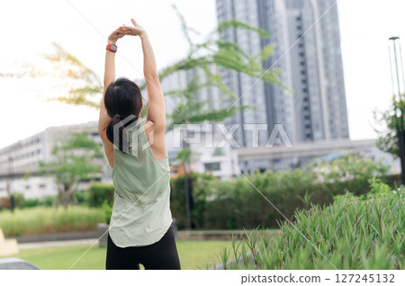 Asian woman 30s fitness yoga workout. Stretching exercise reduces medical injury risk shoulder pain muscle strain inflammation. Healthy lifestyle wellness healthcare an urban city park sunset 127245132