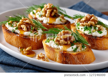Delicious canapes with ricotta, walnuts and honey garnished with dill on white plate 127246000